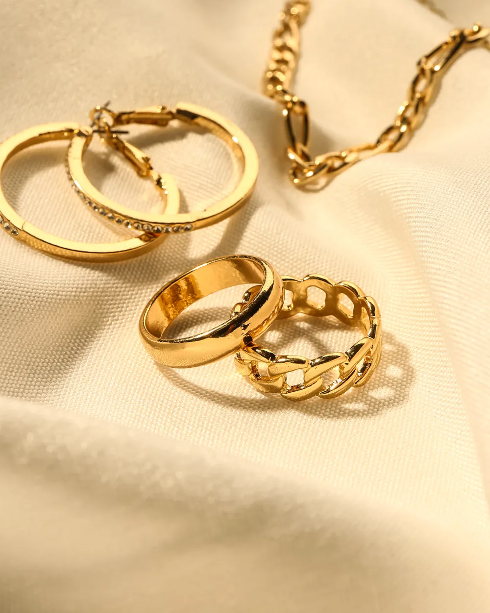 Cincin dan subang emas di atas kain satin sebagai barang kemas yang kekal bernilai