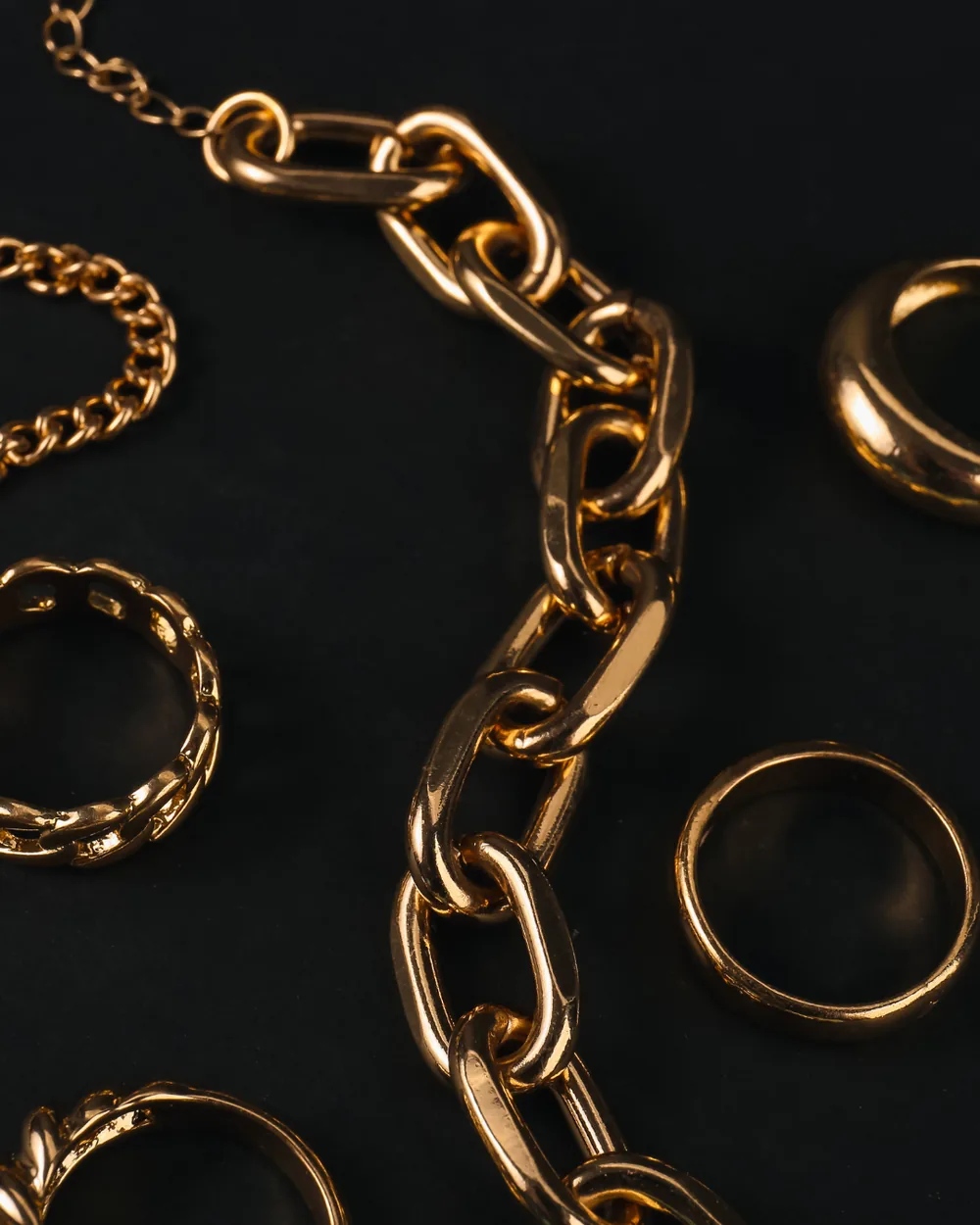 Rantai emas dan cincin di atas latar hitam untuk ujian ketulenan emas
